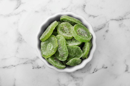 Bowl with slices of kiwi on marble background, top view. Dried fruit as healthy foodの写真素材