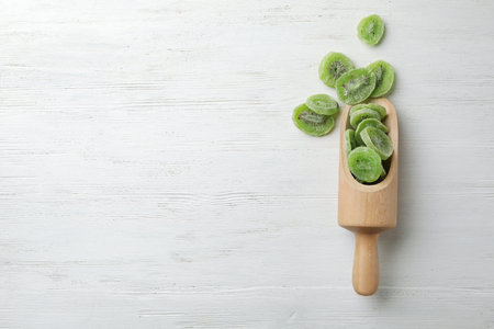 Scoop of dried kiwi on wooden background, top view with space for text. Tasty and healthy fruitsの写真素材
