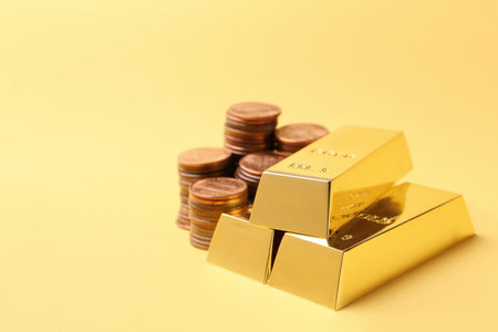 Shiny gold bars and coins on color backgroundの写真素材