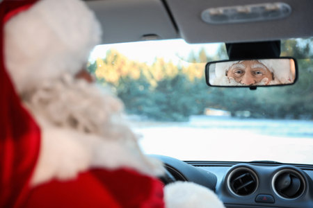 Authentic Santa Claus looking into rear view mirror inside of carの写真素材