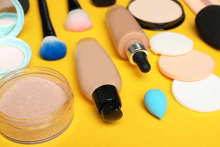 Composition with skin foundation, powder and beauty accessories on color backgroundの写真素材