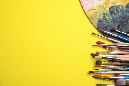 Different paint brushes and palette on color background, top view with space for textの写真素材