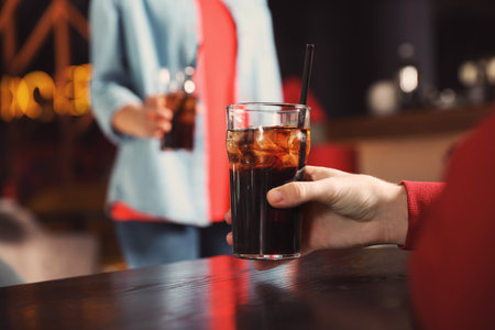 Man holding glass of cola at table in bar, closeup. Space for textの写真素材