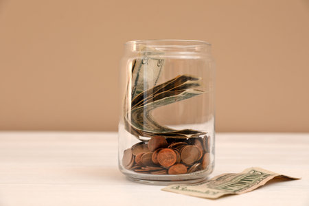 Donation jar with money on table against color backgroundの写真素材