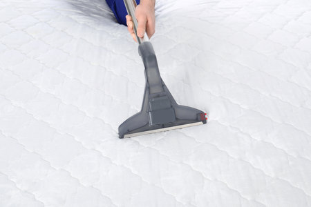 Man disinfecting mattress with vacuum cleaner, closeupの写真素材