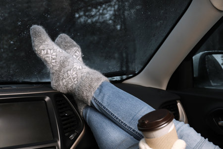 Woman in warm socks with coffee resting inside car, closeupの写真素材