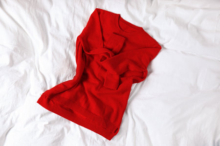 Red cashmere sweater on white fabric, top viewの写真素材