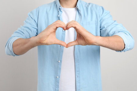 Man making heart with his hands on light background, closeupの写真素材