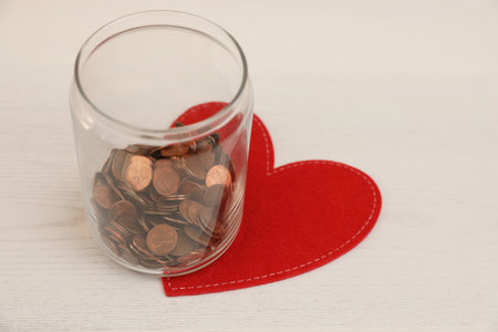 Red heart and donation jar with coins on light backgroundの写真素材