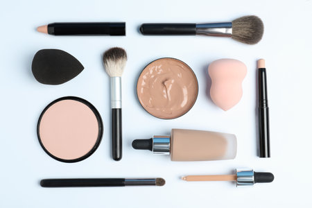Flat lay composition with skin foundation, powder and beauty accessories on white backgroundの写真素材