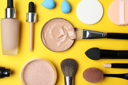 Flat lay composition with skin foundation, powder and beauty accessories on color backgroundの写真素材