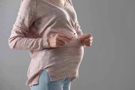 Young pregnant woman breaking cigarette on gray background, closeup. Space for textの写真素材