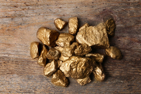 Pile of gold nuggets on wooden background, top view