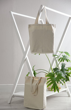 Eco bags with rack and houseplant near white wall. space for designの写真素材