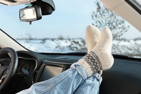 Young woman in warm socks holding her legs on car dashboard. Cozy atmosphereの写真素材