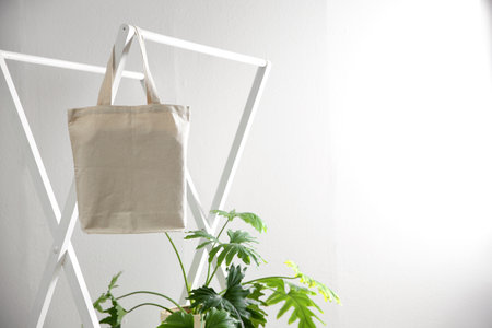 Houseplant and eco bag on rack near white wall. space for designの写真素材