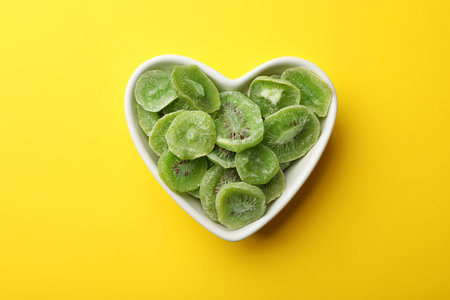 Bowl with slices of kiwi on color background, top view. Dried fruit as healthy foodの写真素材