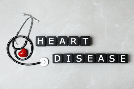 Wooden cubes with text Heart Disease and stethoscope on gray background, flat layの写真素材