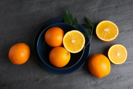 Fresh oranges and bowl on gray table, top viewの写真素材