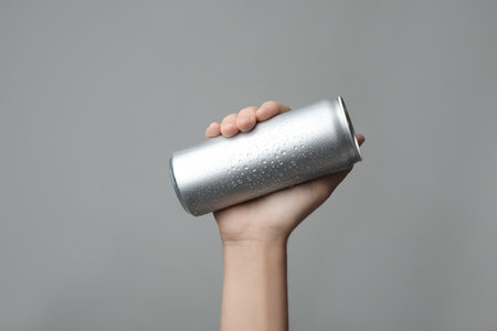 Woman holding aluminum can with beverage on gray background, closeup. space for designの写真素材