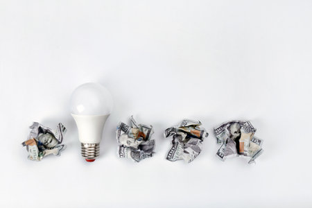 Composition with lamp bulb, crumpled banknotes and space for text on white background, top view. creative conceptの写真素材