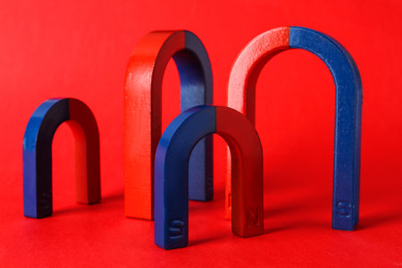 Red and blue horseshoe magnets on color background