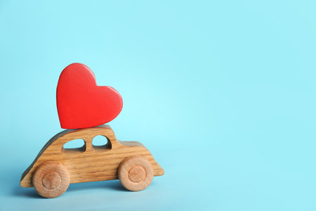 Small wooden car with heart on color background, space for textの写真素材