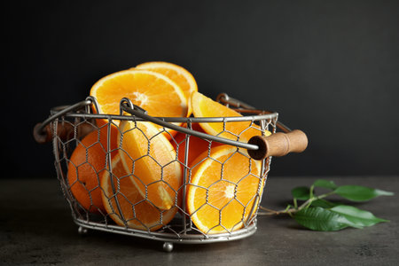 Fresh juicy oranges in basket on gray tableの写真素材