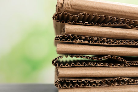 Stack of cardboard for recycling on blurred background, closeup. Space for textの写真素材