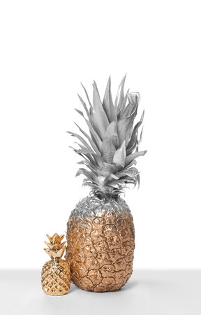 Silver and gold painted pineapple with cute decor on white backgroundの写真素材