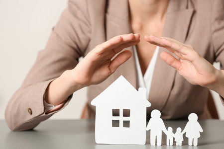 Female agent covering house model and family at table, closeup. home insuranceの写真素材