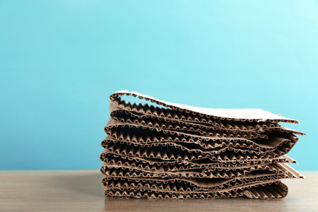 Stack of cardboard for recycling on table against color background. Space for textの写真素材