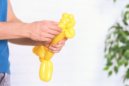 Man making balloon figure on blurred background, closeup. Space for textの写真素材