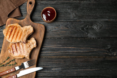 Grilled meat served with sauce on wooden background, flat lay. Space for textの写真素材