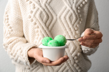 Woman eating snow ice cream from bowl on light background, closeupの写真素材