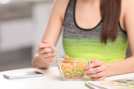 Young woman in fitness clothes having healthy breakfast at home, closeupの写真素材