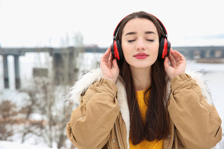 Beautiful young woman listening to music with headphones outdoors. Space for textの写真素材
