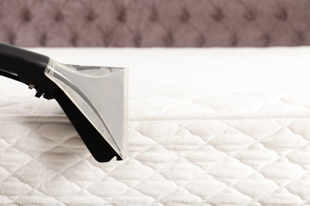 Using modern vacuum cleaner for mattress disinfection, closeup. Space for textの写真素材