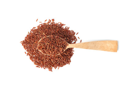 Spoon and uncooked brown rice on white background, top viewの写真素材