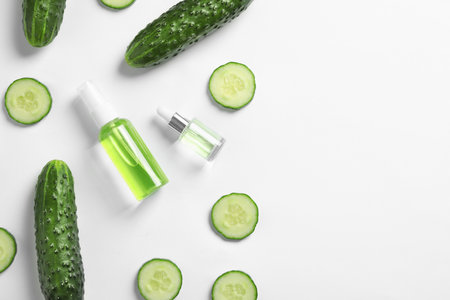 Flat lay composition with fresh cucumber, cosmetic bottles and space for text on white backgroundの写真素材