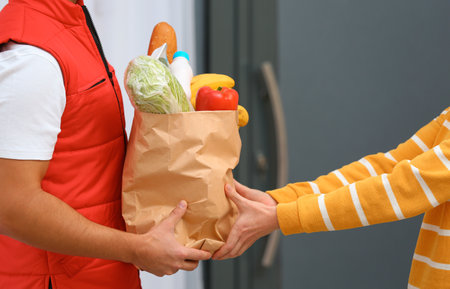 Male courier delivering food to client indoors, closeupの写真素材