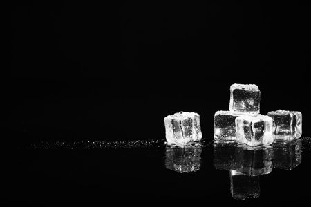 Pile of crystal clear ice cubes on black background. Space for textの写真素材