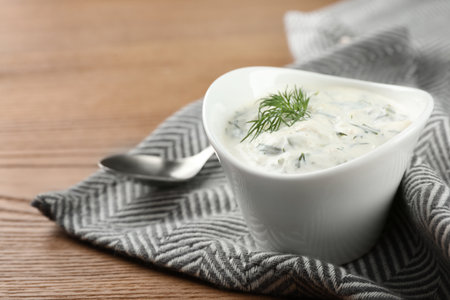Cucumber sauce with spoon on wooden background, space for text. Traditional Tzatzikiの写真素材