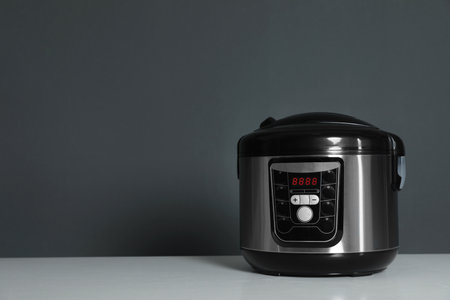 Modern electric multi cooker on table against dark background. Space for textの写真素材