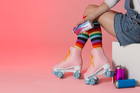 Woman with vintage roller skates and spray paint cans on color background, closeup. Space for text