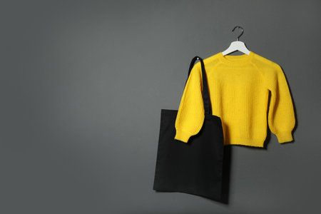 Eco tote bag and sweater hanging on gray wall. Space for textの写真素材