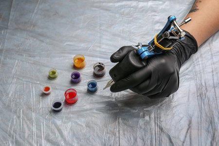 Tattoo artist with machine and inks at table, closeupの写真素材
