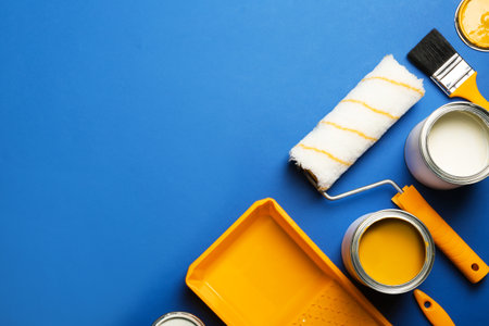 Flat lay composition with paint cans, decorator tools and space for text on color backgroundの写真素材