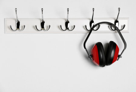 Protective headphones hanging on white wall. safety equipmentの写真素材