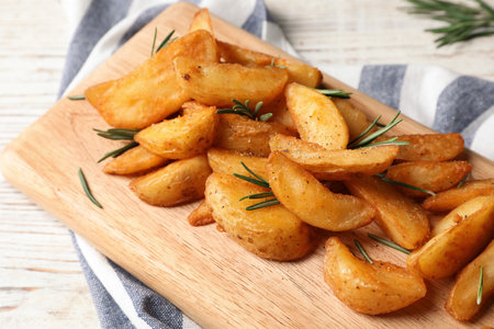 Wooden board with baked potatoes and rosemary on table, closeupの写真素材